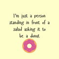 A round, 2-inch fridge magnet with a cartoon donut with pink icing and sprinkles on a yellow background with text, 'I'm just a person standing in front of a salad asking it to be a donut'