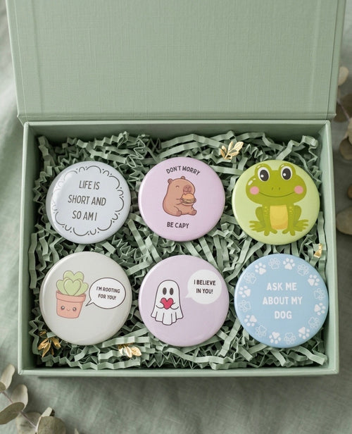 A set of six 2-inch round fridge magnets with various designs, sitting in a decorative box